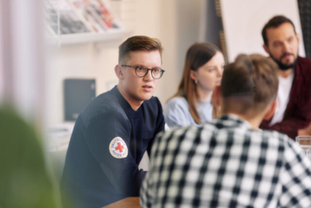 Gruppe Mitarbeitender unterhält sich am Tisch