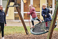 Schaukelnde Kinder in der Nestschaukel, Junge und Mädchen