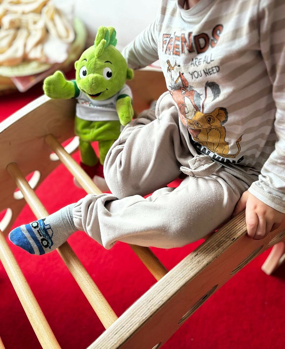 Jolinchen sitzt mit einem Kind am Kletterbogen