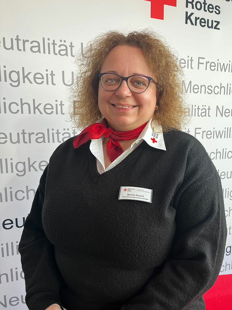Portrait_Eisend_Monika Zeigt Mitarbeitenden mit BRK Oberteil