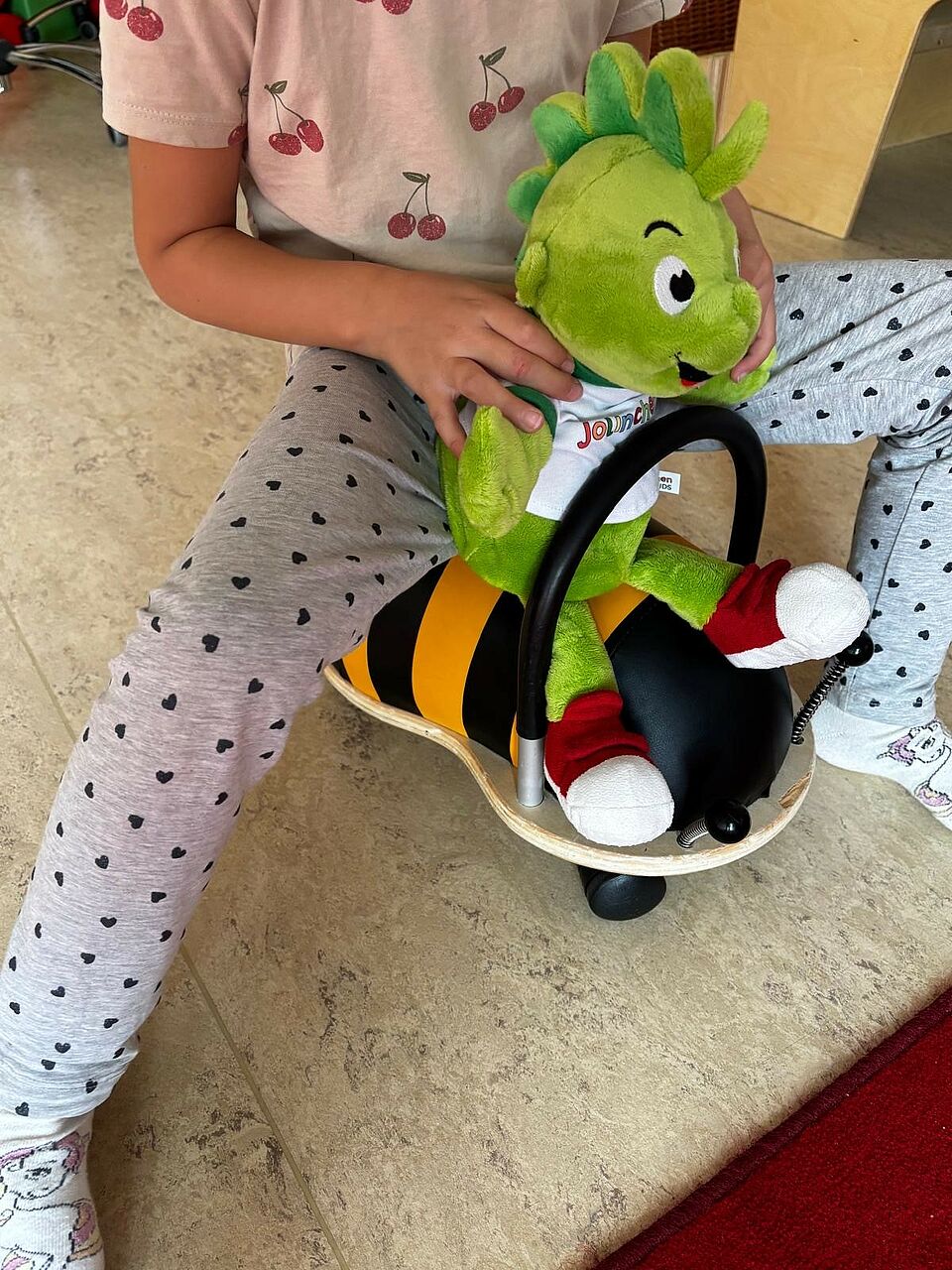 Jolinchen sitzt mit einem Kind auf einem Rutschgefährt