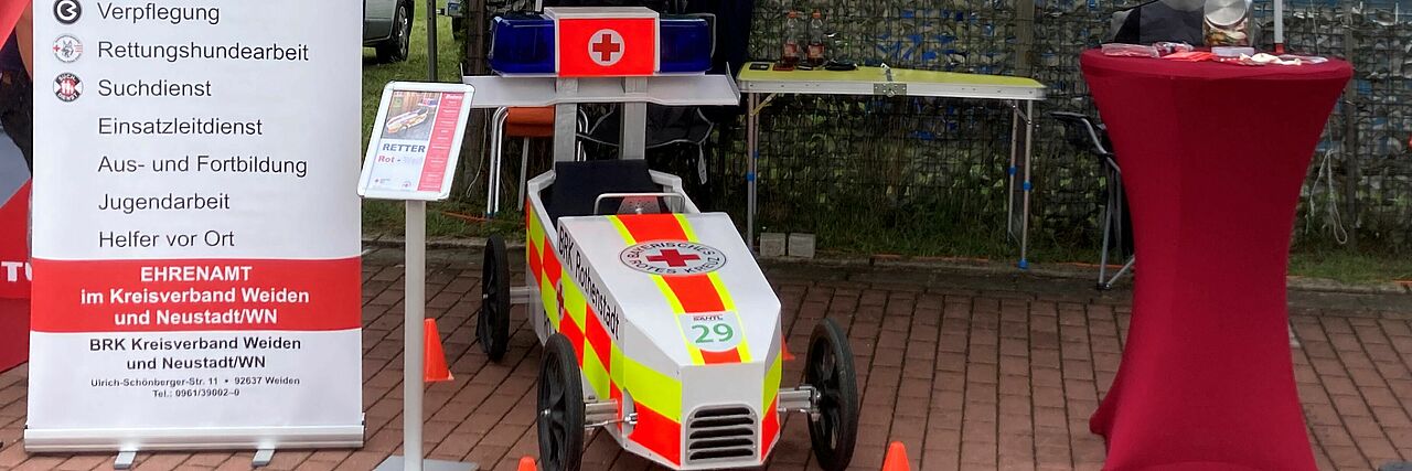Pavillon darunter steht die Seifenkiste, links davon Roll Up mit Infos zur Bereitschaft, rechts roter Stehtisch