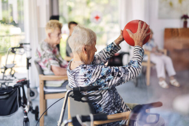 Seniorengruppe im Kreis, spielen mit einem roten Ball