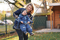 Schaukelndes Kleinkind mit Erzieherin in Babyschaukel