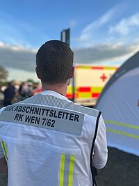 Abschnittsleiter mit weißer Weste, Hintergrund RTW und Veranstaltung