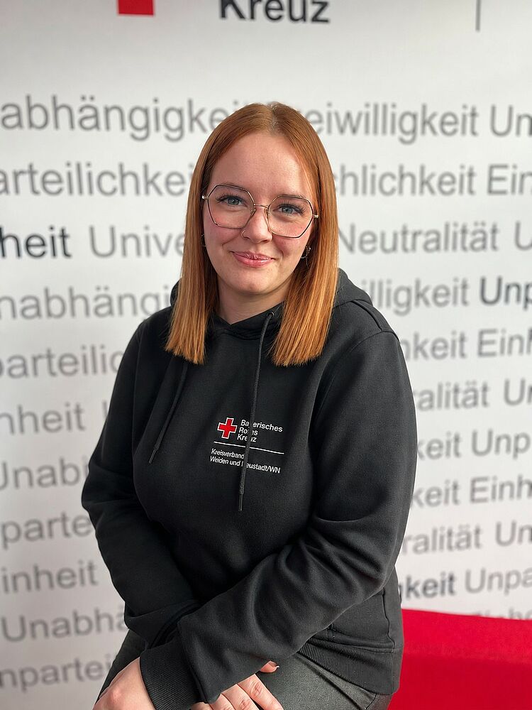 Portrait_Hierold_Julia Zeigt Mitarbeitenden mit BRK Oberteil