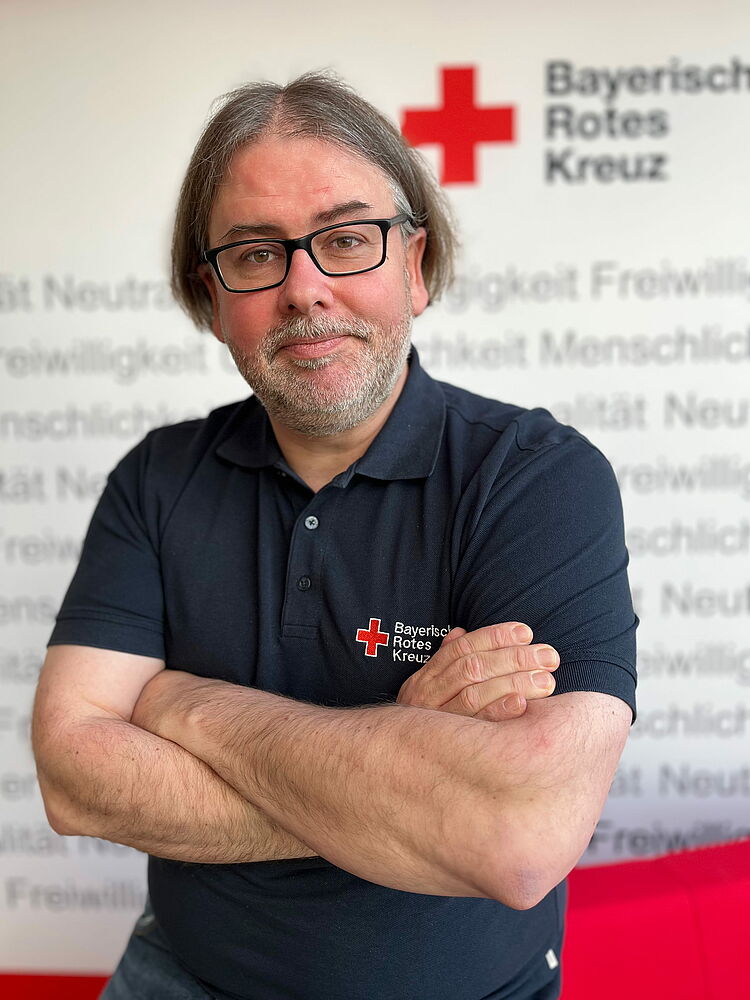 Portrait_Gradl_Thorsten Zeigt Mitarbeitenden mit BRK Oberteil