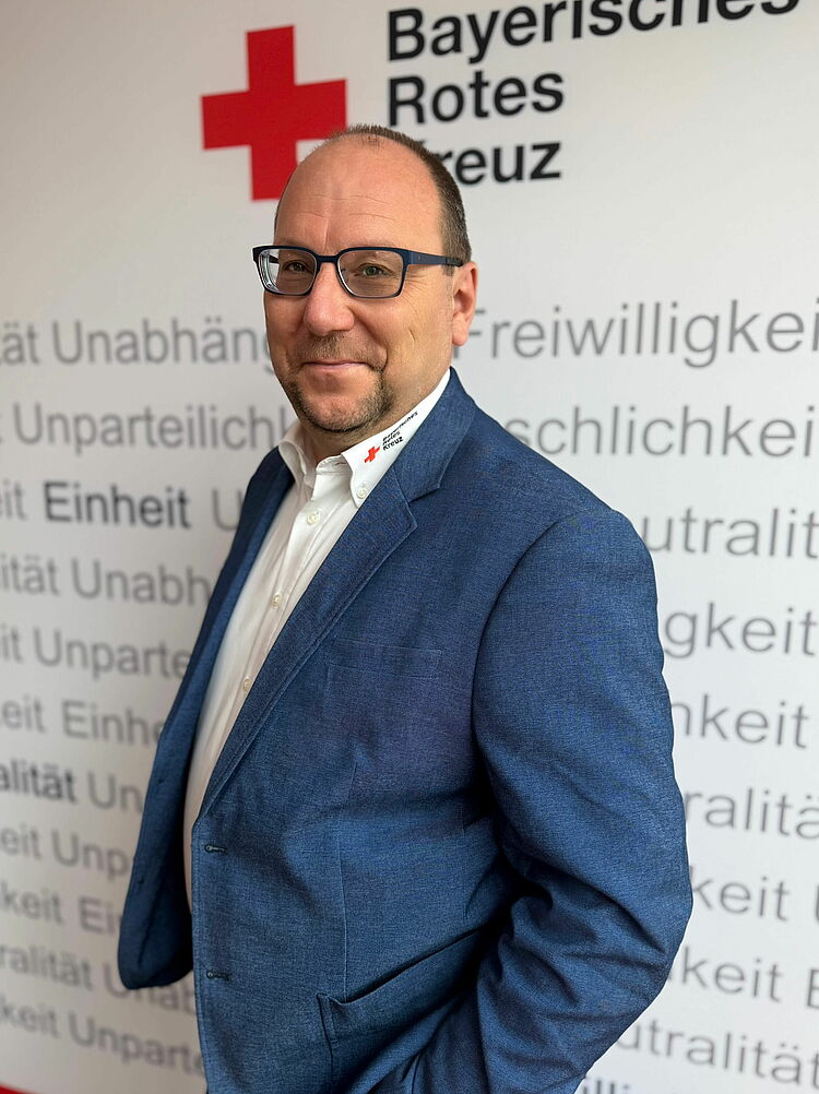 Portrait_Wöhrl_Andreas Zeigt Mitarbeitenden mit BRK Oberteil